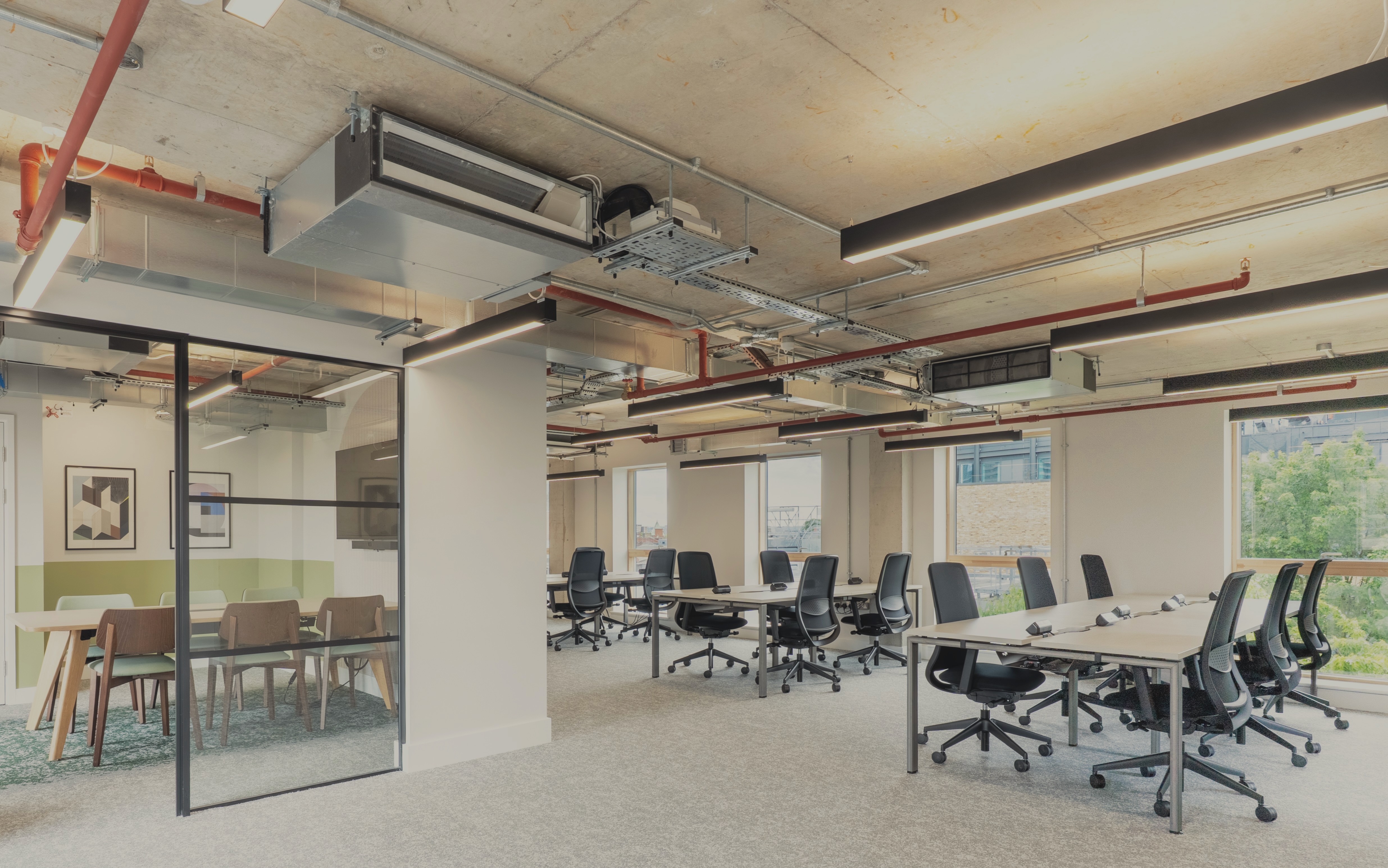 Open-plan desks beside a glass-walled meeting room